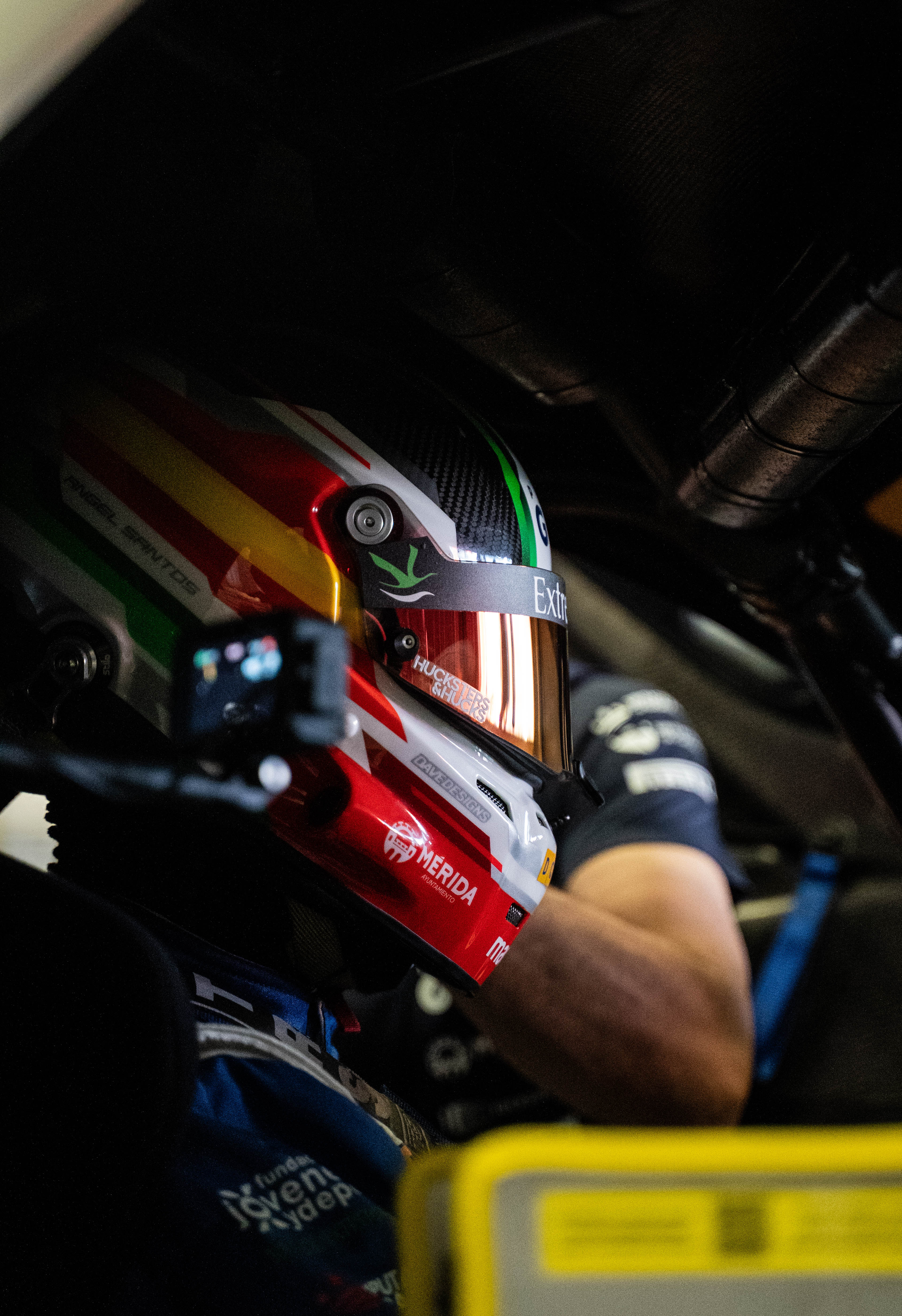 Primer plano de un piloto con casco multicolor y visor dorado en el interior de un coche de competición